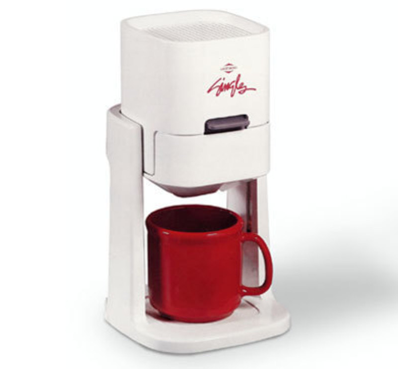 Three quarters front view of the singles coffee maker with a red coffee mug inside